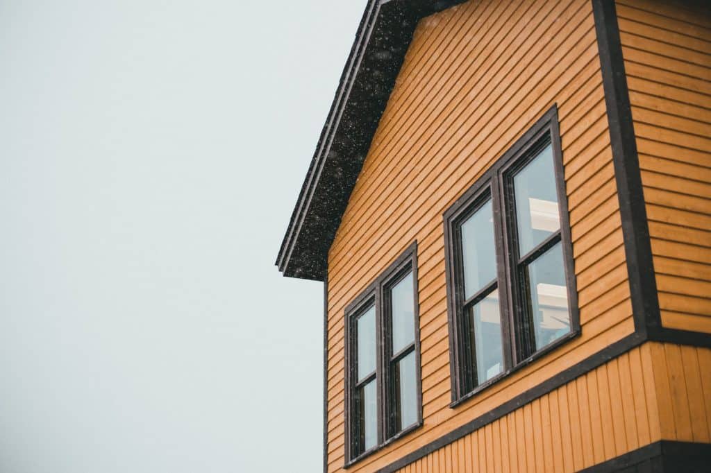 Homeowner inspecting and sealing house siding before hurricane season in New Orleans