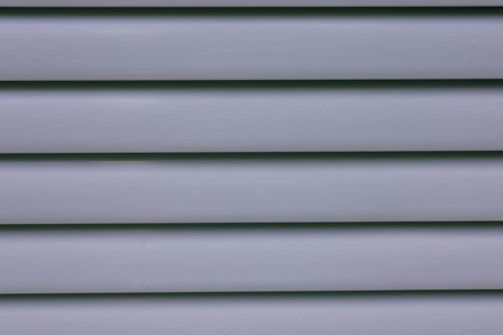 Homeowner inspecting and cleaning the siding on a New Orleans style home