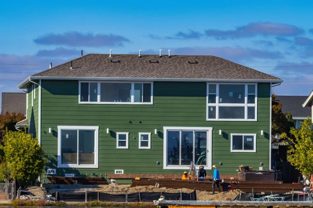 Siding crew installing lap siding on a raised home in New Orleans