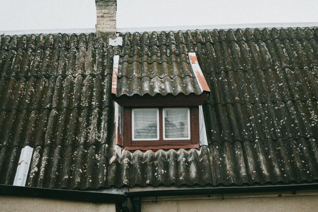 Weathered corrugated cement roof sheets around a dormer, an older cement material to test before work in Metairie