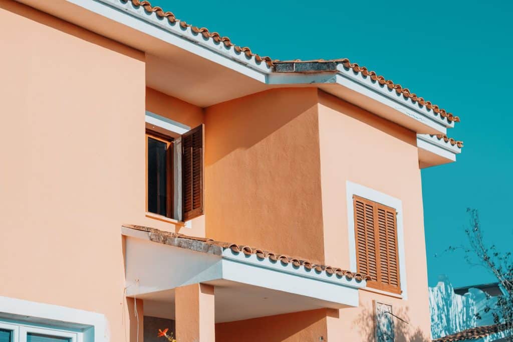 Smooth stucco walls and wood shutters on a two-story house, the finish Metairie owners check for EIFS or stucco